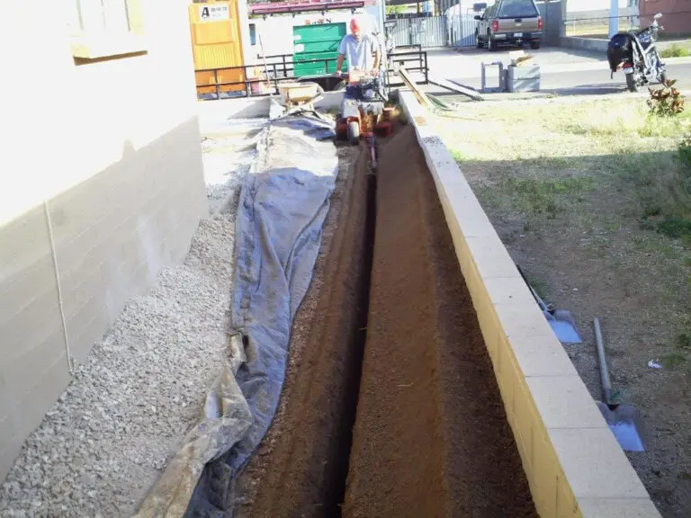 Person working in a narrow trench outdoors.