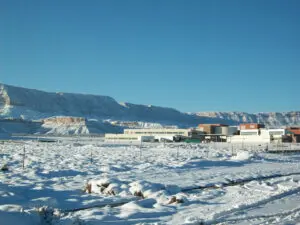 Snow-covered landscape with distant buildings and mountains.