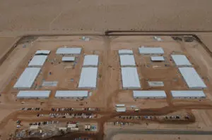 Aerial view of desert buildings and vehicles.