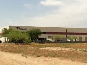 Industrial building with Triumph logo and trees.