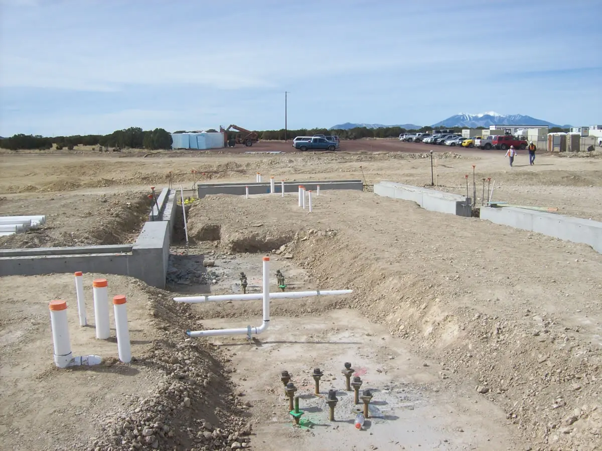 Construction site with pipes and concrete foundation.