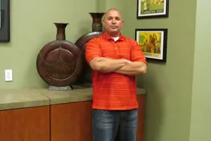 Man in orange shirt standing with arms crossed.