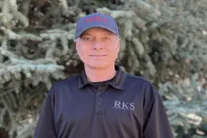 Man in black shirt and cap outdoors.