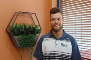 Man smiling beside wall-mounted plant decor.